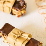 Two chocolate-topped Kind Bars wrapped in brown paper and tied with string are placed on a light-colored surface.